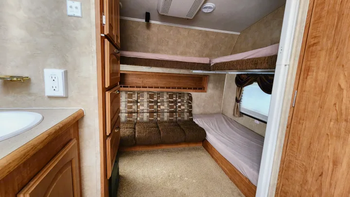 Cozy RV rental interior featuring bunk beds, a comfortable sofa, and a compact sink area, perfect for family adventures.. Forest River Wildcat 2008
