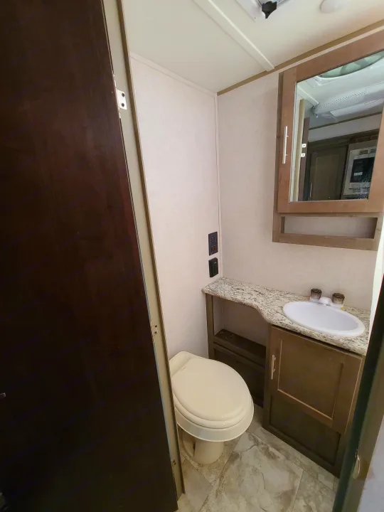 A well-equipped RV rental bathroom features a compact toilet, vanity with sink, and mirror for convenience.. Forest River R-Pod 2018