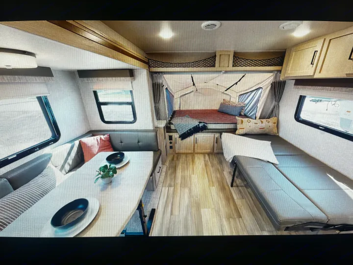 Bright RV rental interior featuring a functional dinette, an expandable canvas bed, built-in storage, and seating.. Forest River Flagstaff Shamrock 2022