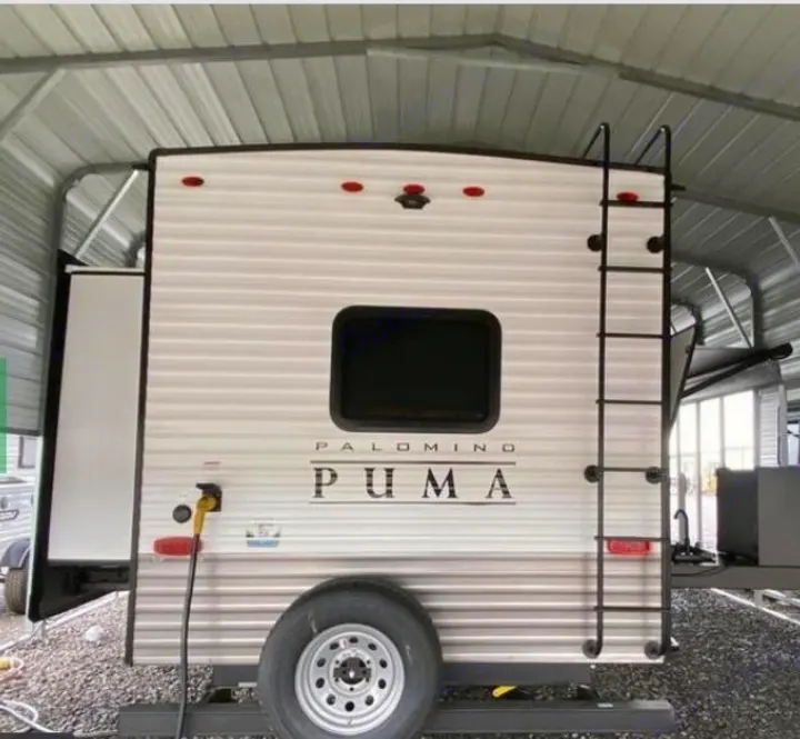 Rear view of a Palomino Puma travel trailer, perfect for your next RV rental. Features a spare tire and ladder.. Forest River Palomino Puma 2022
