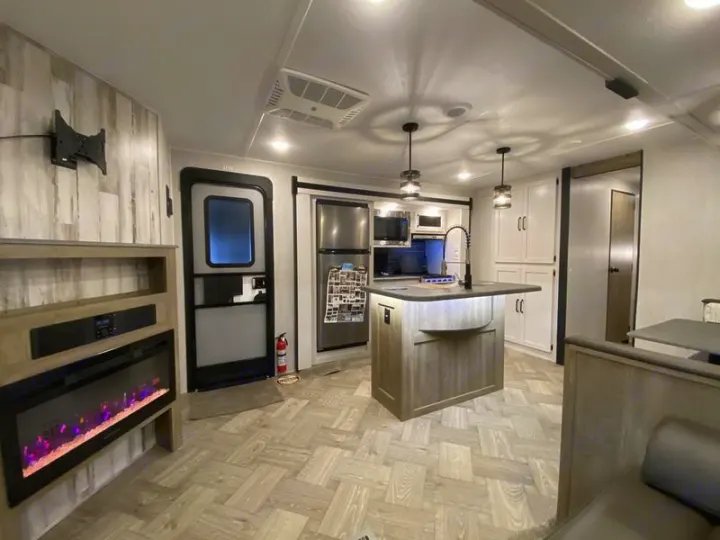Explore this modern rv rental interior, featuring a bright kitchen island, fireplace, and comfortable living space.. Forest River Palomino Puma 2022