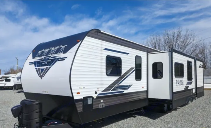 White and black Puma travel trailer, ideal for an rv rental adventure, with an extended slide-out section.. Forest River Palomino Puma 2022