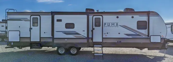 Side view of a light grey Puma Palomino travel trailer RV, with dark stripes, two doors, and windows, available for rv rental.. Forest River Palomino Puma 2022