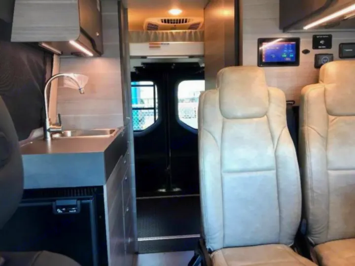 Spacious rv rental interior with kitchenette, fridge, comfy seating, and overhead bed area. Perfect for travel adventures!. Mercedes-Benz Entegra Launch 2023