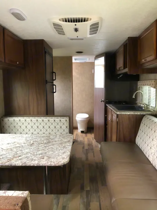 RV rental interior with kitchen, dining booth, sofa, and bathroom visible. Functional and compact living space.. Forest River Viking 2018