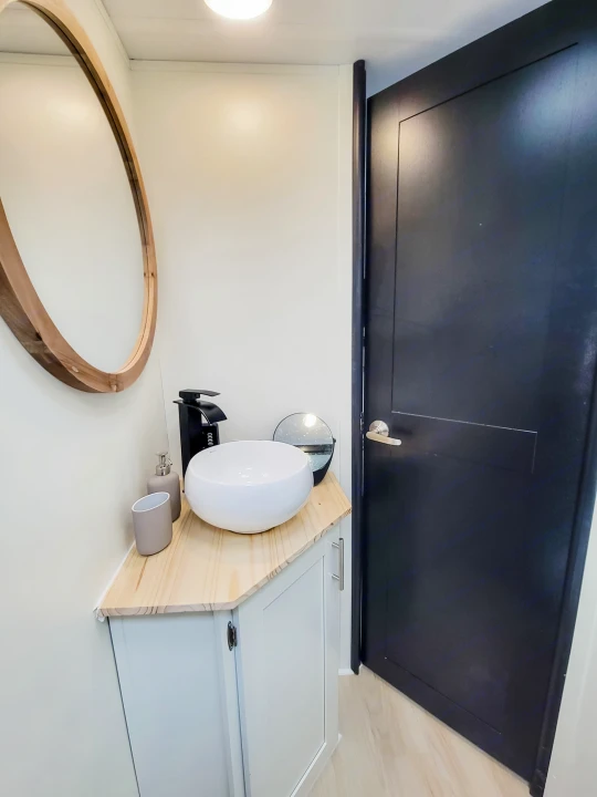 Modern RV rental bathroom with a stylish vessel sink, wood vanity, and round mirror.. Forest River Tracer 2022