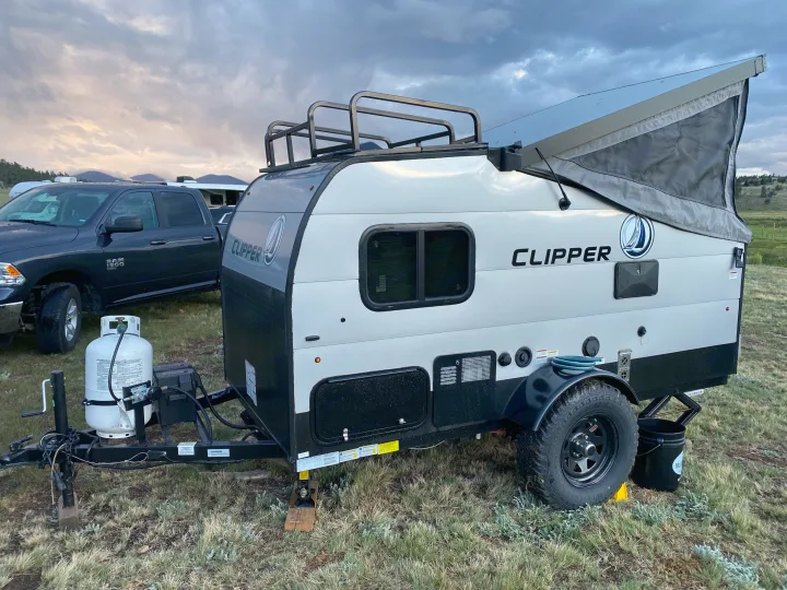 This Clipper pop-top travel trailer rv rental is ready for outdoor adventure, parked under a cloudy sky.. Coachmen Clipper 2021
