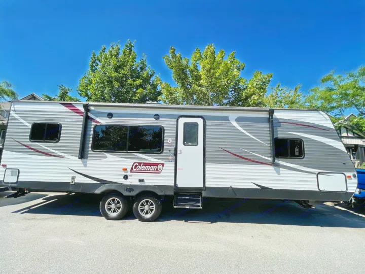 Spacious white and gray Coleman rv rental travel trailer parked under a clear blue sky, ready for your next outdoor adventure.. Coleman Lantern 28.6 RK 2018