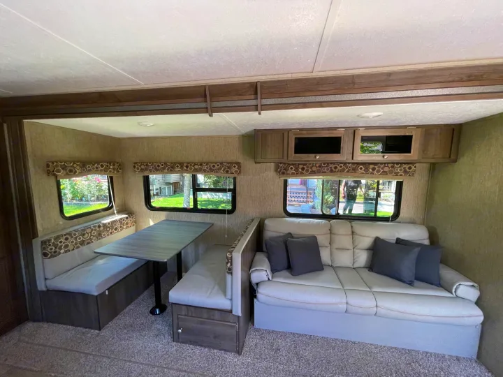 RV rental interior: A bright living area featuring a dinette with bench seating and a comfortable sofa.. Coleman Lantern 28.6 RK 2018