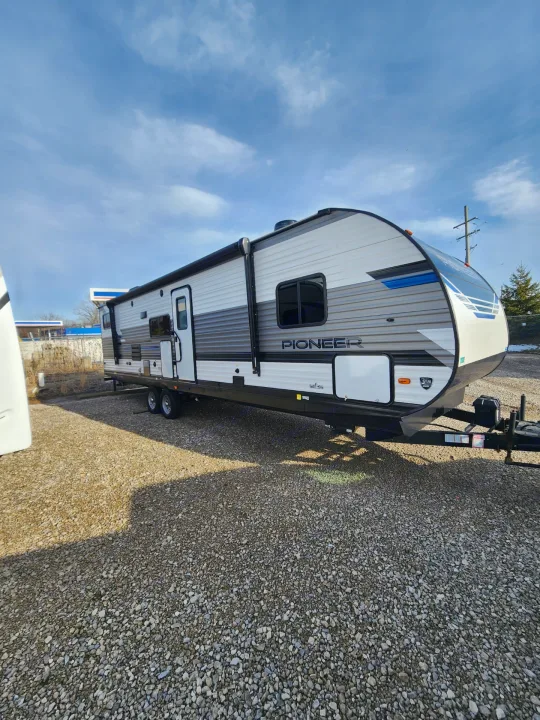 Bright white & grey Pioneer travel trailer on a gravel lot, under blue skies. Great for your next rv rental trip!. 5SFPB372XME475890 Pioneer 2021
