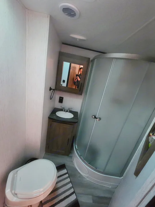 Functional RV rental bathroom: white toilet, sink, vanity, and a space-saving curved shower.. 5SFPB372XME475890 Pioneer 2021