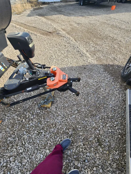 Close-up of an RV rental trailer hitch and weight distribution system on a gravel lot, ready for towing.. 5SFPB372XME475890 Pioneer 2021