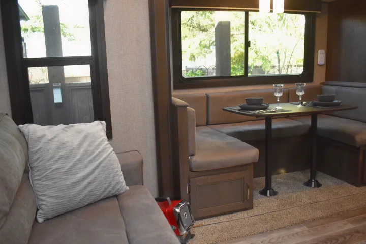 Cozy RV rental interior featuring a comfortable dinette with place settings and a relaxing sofa, ideal for travel.. Jayco Jay Flight SLX Rocky Mountain Edition 2021