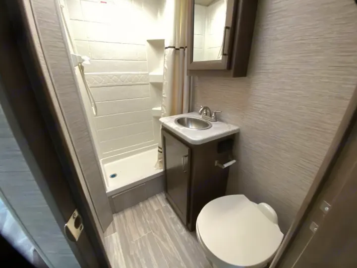 RV rental bathroom: A compact space with a stand-up shower, sink vanity, and toilet, perfect for travel comfort.. Thor Freedom Elite 2021