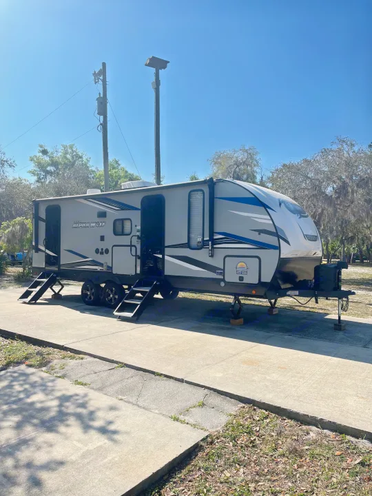 This Cherokee Alpha Wolf travel trailer, a great rv rental option, is parked on a concrete pad in a sunny spot.. Forest River Cherokee Alpha Wolf 2022