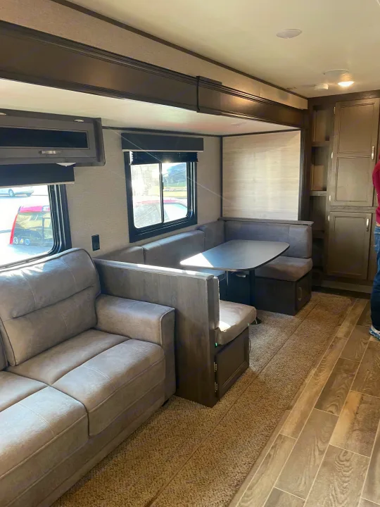 Spacious RV rental living area with a comfortable gray sofa, U-shaped dinette, and ample storage, ready for adventures.. Jayco Jay Flight 2021