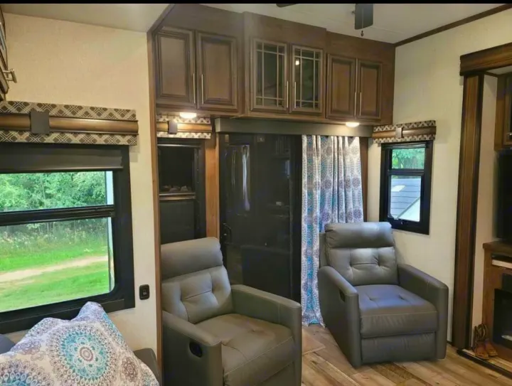 Spacious RV rental interior featuring comfy recliners, overhead cabinets, and large windows for scenic views.. KZ Durango 2021