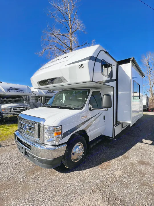 New white Class C RV, likely an rv rental, parked on a gravel lot under clear blue skies, ready for outdoor adventures.. Forest River Sunseeker 2024
