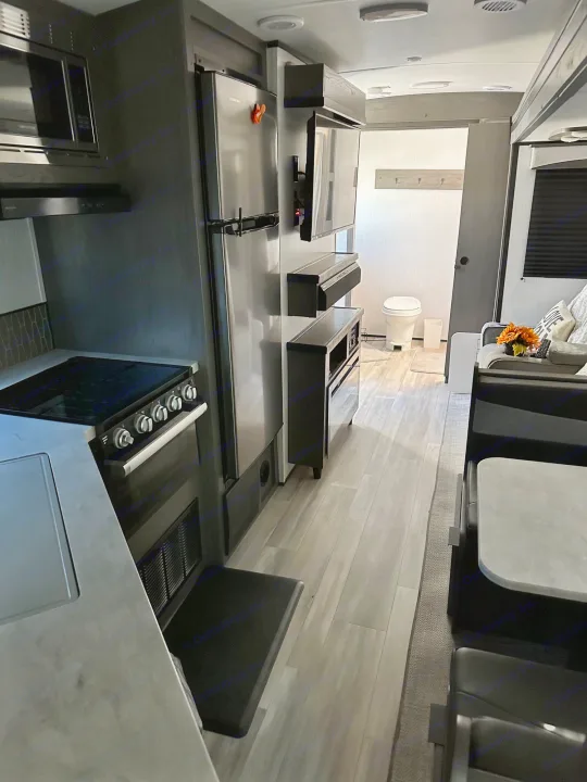 Spacious RV rental interior, showcasing a modern kitchen, living area, and a visible bathroom beyond, perfect for travel.. Cruiser RV Embrace Ultra Lite 2022