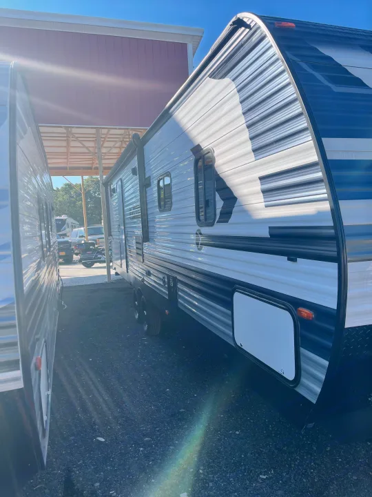 A sleek grey and black travel trailer, available for RV rental, parked outdoors on a sunny day.. Crossroads RV Zinger Lite 2021