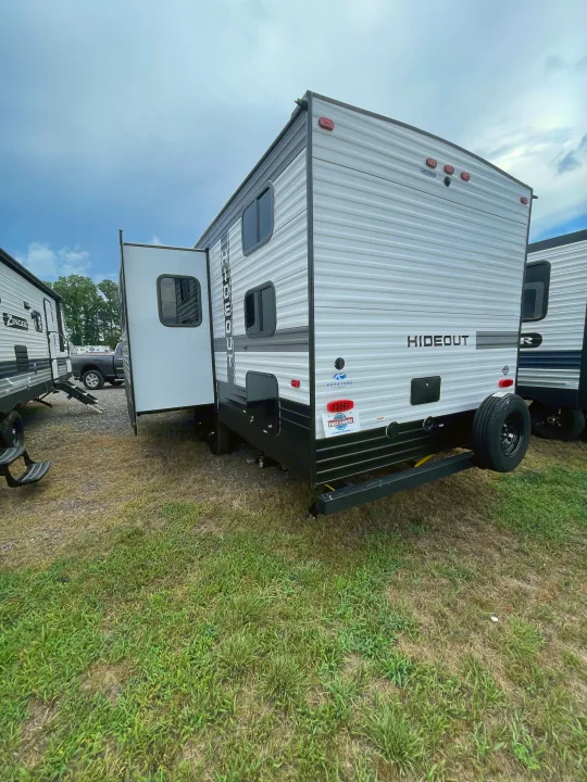 White 'Hideout' travel trailer with slide-out extended, displayed on a lot; a prime option for RV rental.. Keystone RV Hideout 2022