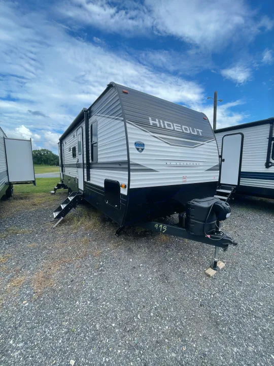 This gray Hideout travel trailer, an RV rental option, is parked on a gravel lot under a partly cloudy sky.. Keystone RV Hideout 2022