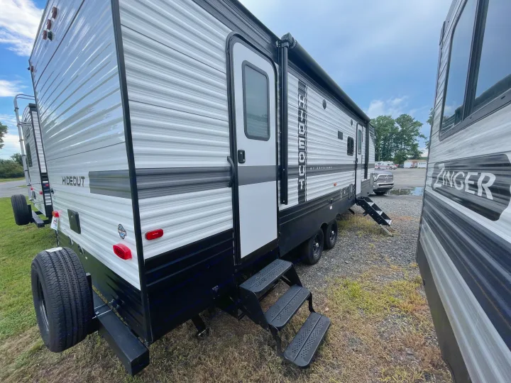 White & gray travel trailer for rv rental. A Keystone Hideout model with extended steps, perfect for outdoor adventures.. Keystone RV Hideout 2022