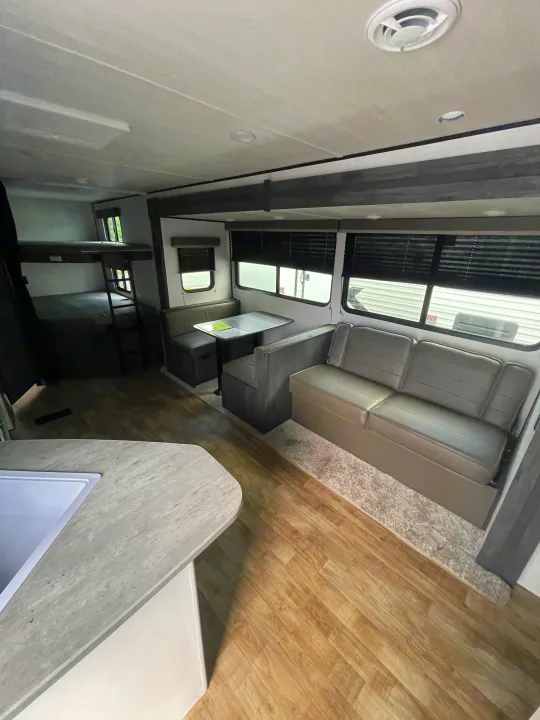 Spacious rv rental interior: modern living area with dinette, sofa, bunk beds, and kitchen sink.. Keystone RV Hideout 2022