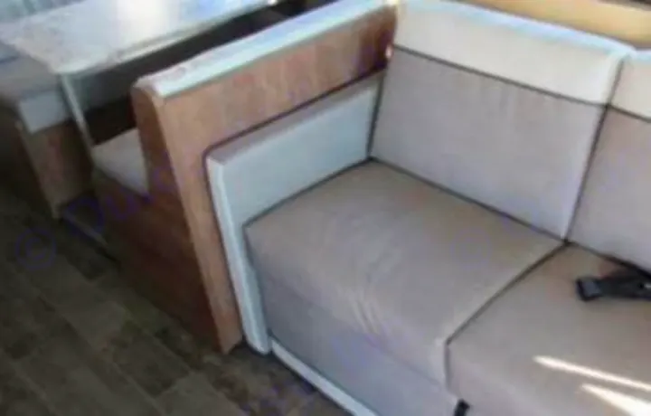 Experience comfort in this RV rental. Interior shows a modern dinette booth opposite a beige sofa with dark trim, ready for travel.. Winnebago Intent 2018