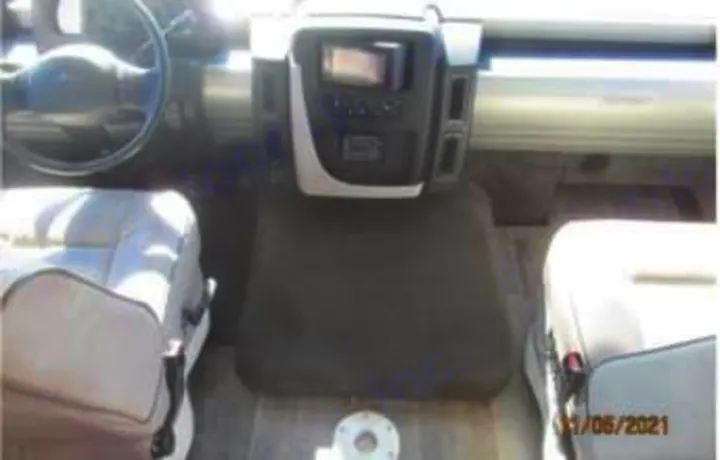RV rental interior: A bright RV cockpit showing the steering wheel, dashboard with screen, and two light-colored captain's chairs.. Winnebago Intent 2018