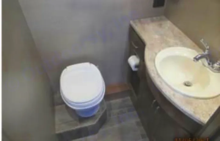 Interior of an RV rental bathroom, showing a white toilet on a raised platform next to a vanity with a sink.. Winnebago Intent 2018