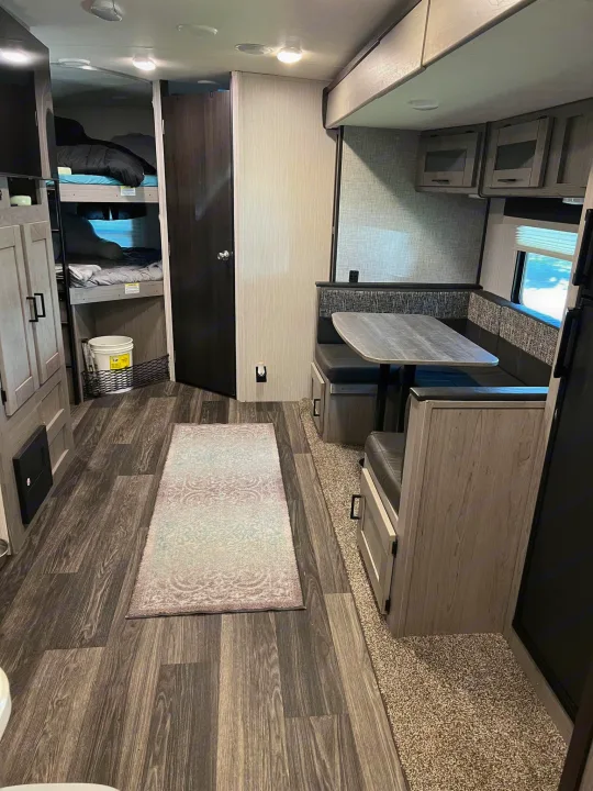 Step inside this RV rental's inviting interior, showcasing bunk beds, a comfy dinette, and stylish wood-look floors.. Heartland RVs Mallard 2021
