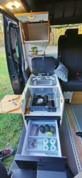 Explore with our RV rental! This compact campervan kitchen has a sink, portable stove, and fridge, ready for your road trip meals.. Renault Trafic 2023