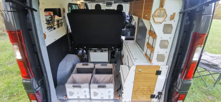 Inside a well-equipped RV rental: fold-down bed, custom storage, magazine rack, and "CAR CAR" bins.. Renault Trafic 2023