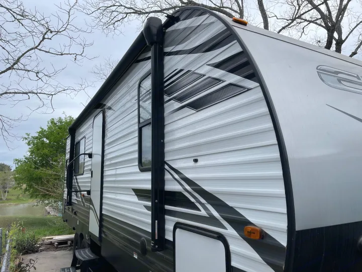 Sleek RV rental, white with black graphics, parked outdoors by a lake with bare trees overhead.. Forest River Evo 2022