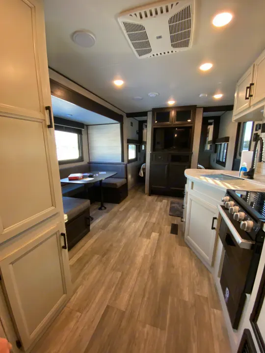 Spacious, modern RV rental interior featuring a comfortable dining booth, full kitchen, and entertainment center.. JAYFLIGHT 242BHSW-G 2023