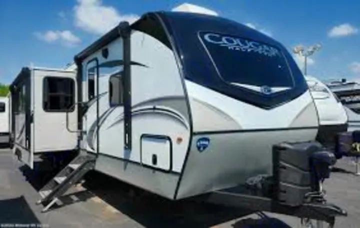 This white & grey travel trailer, with awning out and steps down, is ideal for your next RV rental & camping adventure!. Keystone Cougar 2023