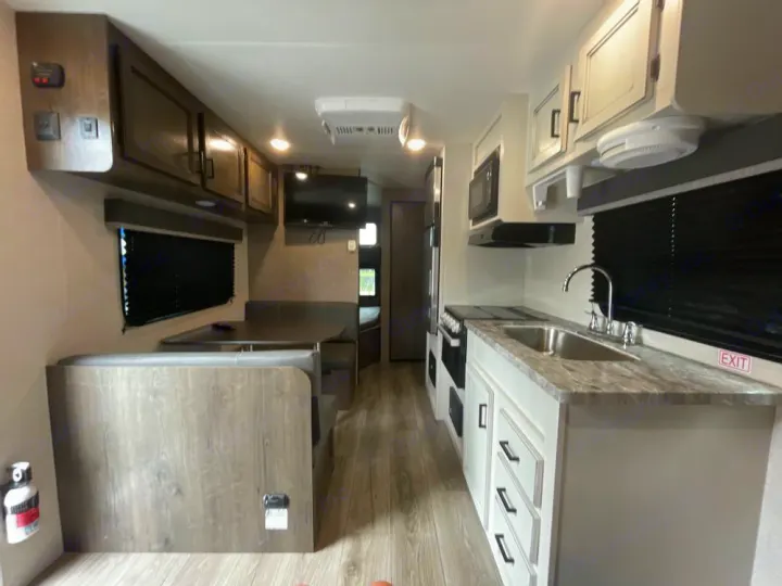 Spacious RV rental interior featuring a dinette, kitchen with stove & sink, and overhead cabinets. Ideal for travel.. Highland Ridge RV Open Range 2021