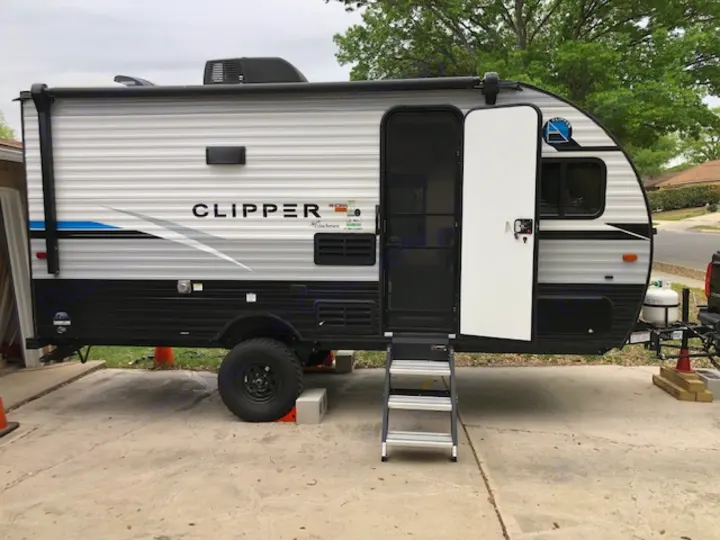 Clean, modern Clipper travel trailer RV rental, parked on a paved lot with its door open and steps extended.. Forest River Coachmen RV Clipper Ultra-Lite 17BH 2022