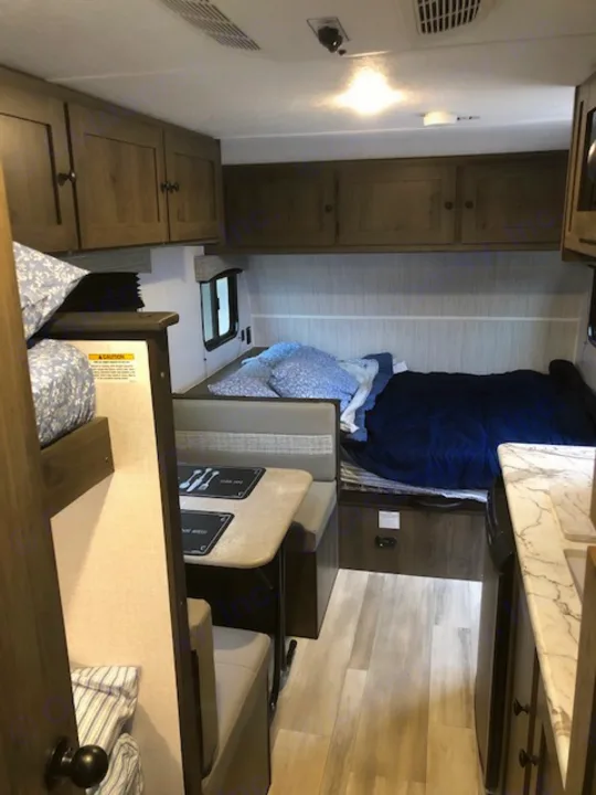 RV rental living space featuring a cozy bedroom, light wood cabinetry, and a spacious dinette with a kitchen counter.. Forest River Coachmen RV Clipper Ultra-Lite 17BH 2022