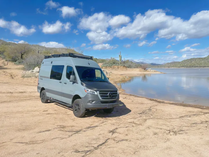 Gray Mercedes Sprinter camper van for rv rental, parked lakeside in a desert landscape under a blue sky.. Mercedes-Benz Entegra Launch 2023