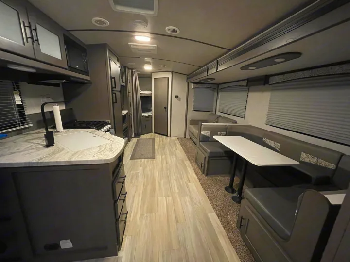 Modern rv rental interior showing kitchen, dining area, and bunk beds, perfect for family adventures.. Cruiser RV MPG Ultra Lite 2021