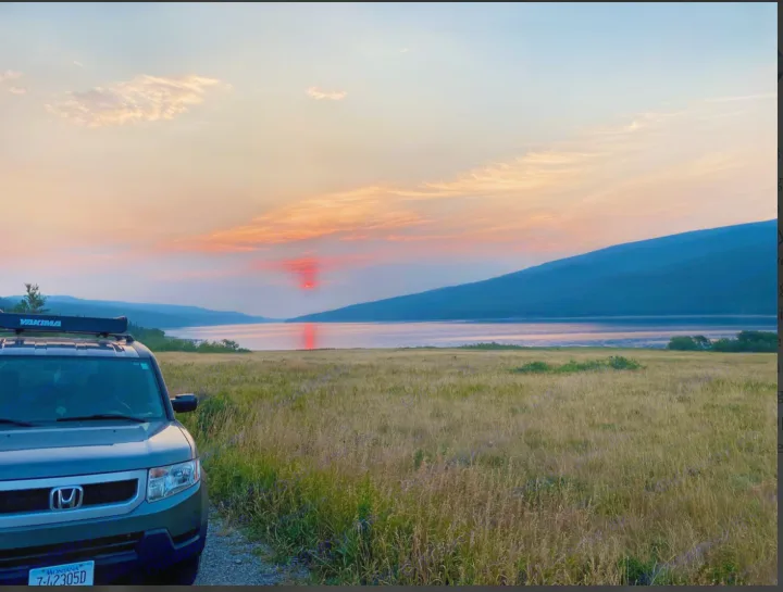 A grey Honda Element with a roof rack overlooks a stunning lake sunset in Montana, a great spot for an rv rental trip.. Honda Element 2009