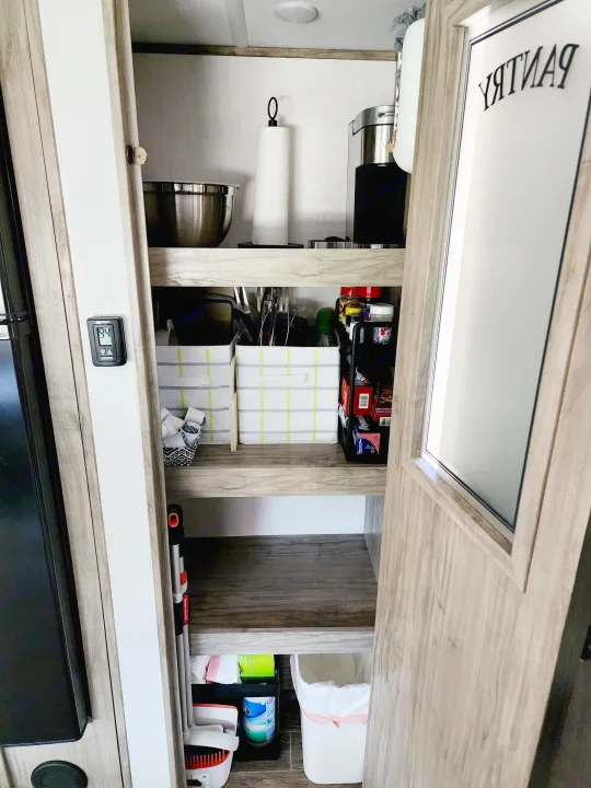 RV rental pantry showcasing organized kitchen essentials, cleaning supplies, and smart storage solutions.. Forest River Cherokee Alpha Wolf 2022