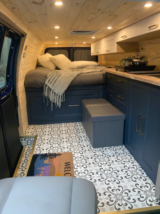 Explore this stylish RV rental interior! Warm wood walls, navy cabinets, & patterned tile floor create a cozy mobile home.. Ford E350 Box Van 2010