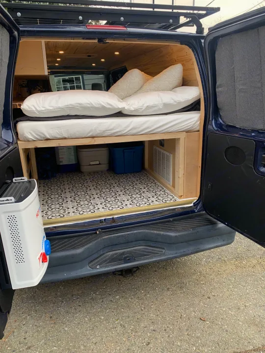 RV rental ready: Peek inside a custom camper van with a cozy bed, clever storage, and a portable water heater.. Ford E350 Box Van 2010