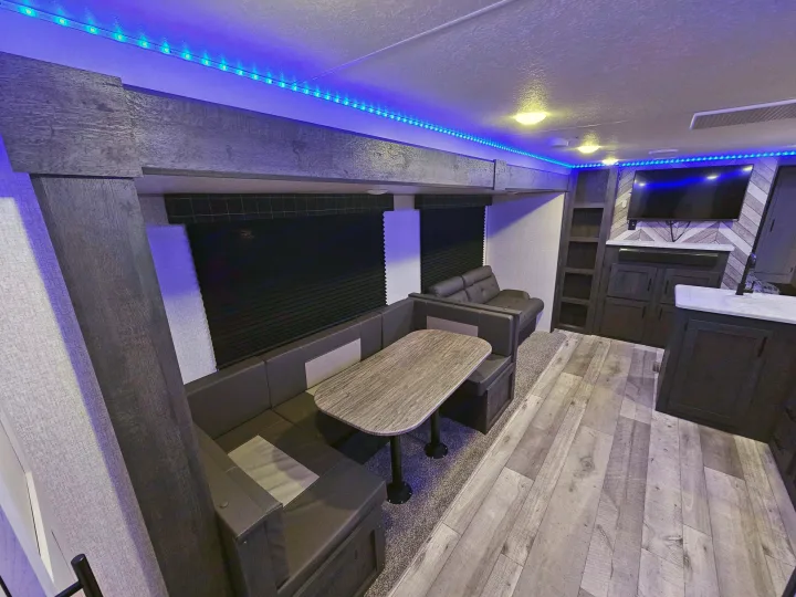 RV rental interior: modern living space with blue LED lighting, U-shaped dinette, and entertainment area.. KZ 312 Bunk House 2022