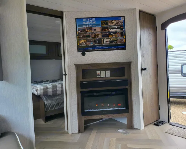RV rental interior: cozy bedroom visible through doorway, electric fireplace unit, and a display poster. Ready for travel!. Forest River Salem 2022