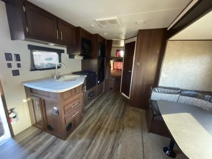 Spacious RV rental interior featuring a well-equipped kitchen, dining booth, and rear bunk beds, offering comfortable living space.. Jayco Jay Flight SLX 2019