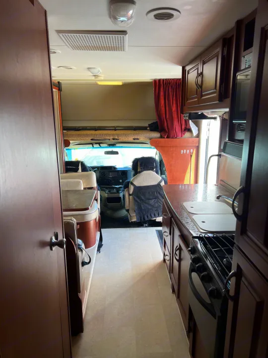 Interior view of an **rv rental**, featuring a full kitchen, comfortable dinette, and front cockpit with a cab-over bed.. Winnebago Minnie Winnie 2015